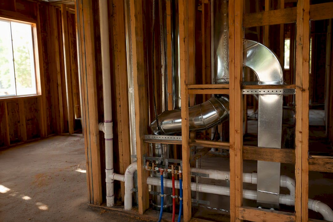Exposed ductwork and plumbing in framed house